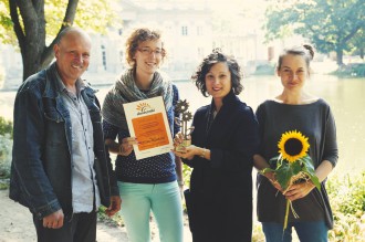 Cztery osoby odpowiedzialne za stworzenie wystawy "Przez dziurkę od klucza" na tle Pałacu na Wyspie trzymają nagrodę w konkursie "Słoneczniki", dyplom i słonecznika.