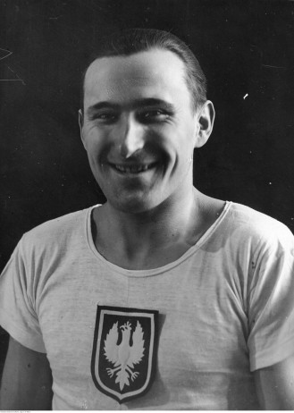Czarno-biała fotografia. Janusz Kusociński w koszulce z Orłem Białym na piersi.