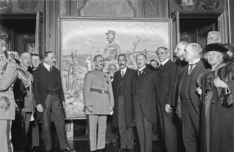 Czarno-biała fotografia. Na pierwszym planie grupa elegancko ubranych osób, w środku marszałek Foch. W tle obraz Wojciecha Kossaka przedstawiający marszałka Focha.