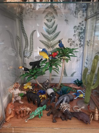 Kilkanaście figurek egzotycznych ssaków i ptaków oraz figurka wysokiego kaktusa i palmy